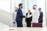 Emirati and corporate professionals shake hands in a modern UAE office, representing Emiratisation and workforce integration.